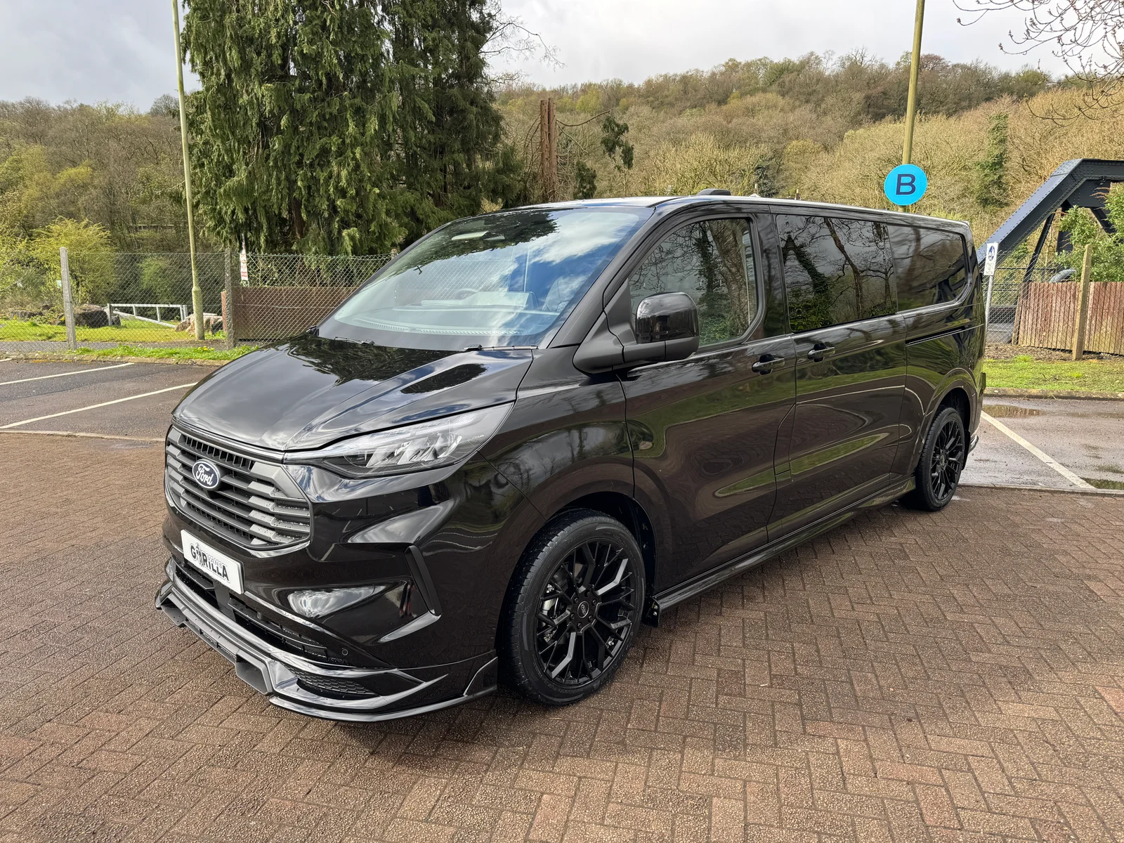 Ford Transit Custom L2 DCIV GV Sport in Agate Black with barn doors — front three-quarter